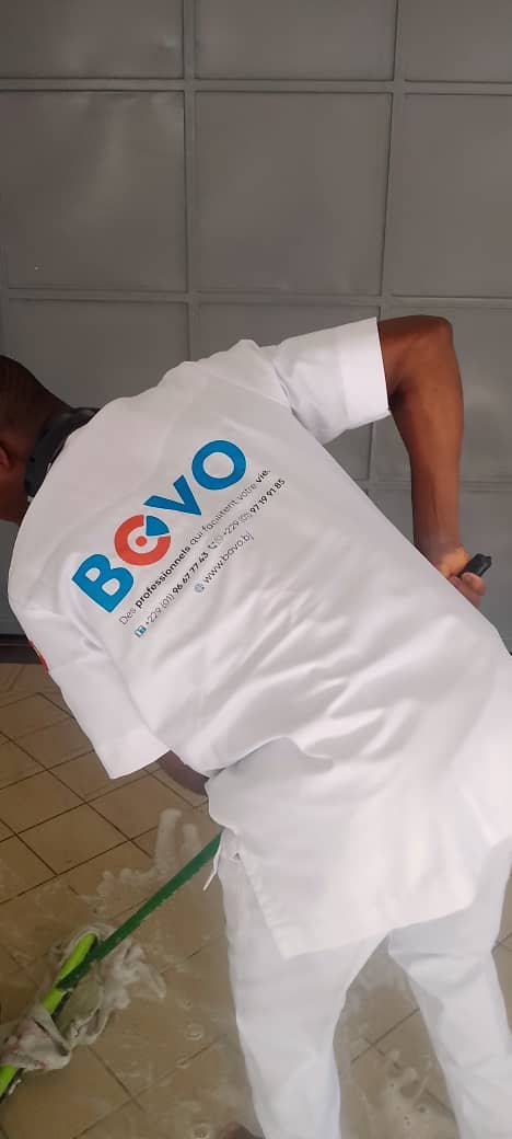Agent Bovo nettoyant un sol carrelé en uniforme officiel à Cotonou