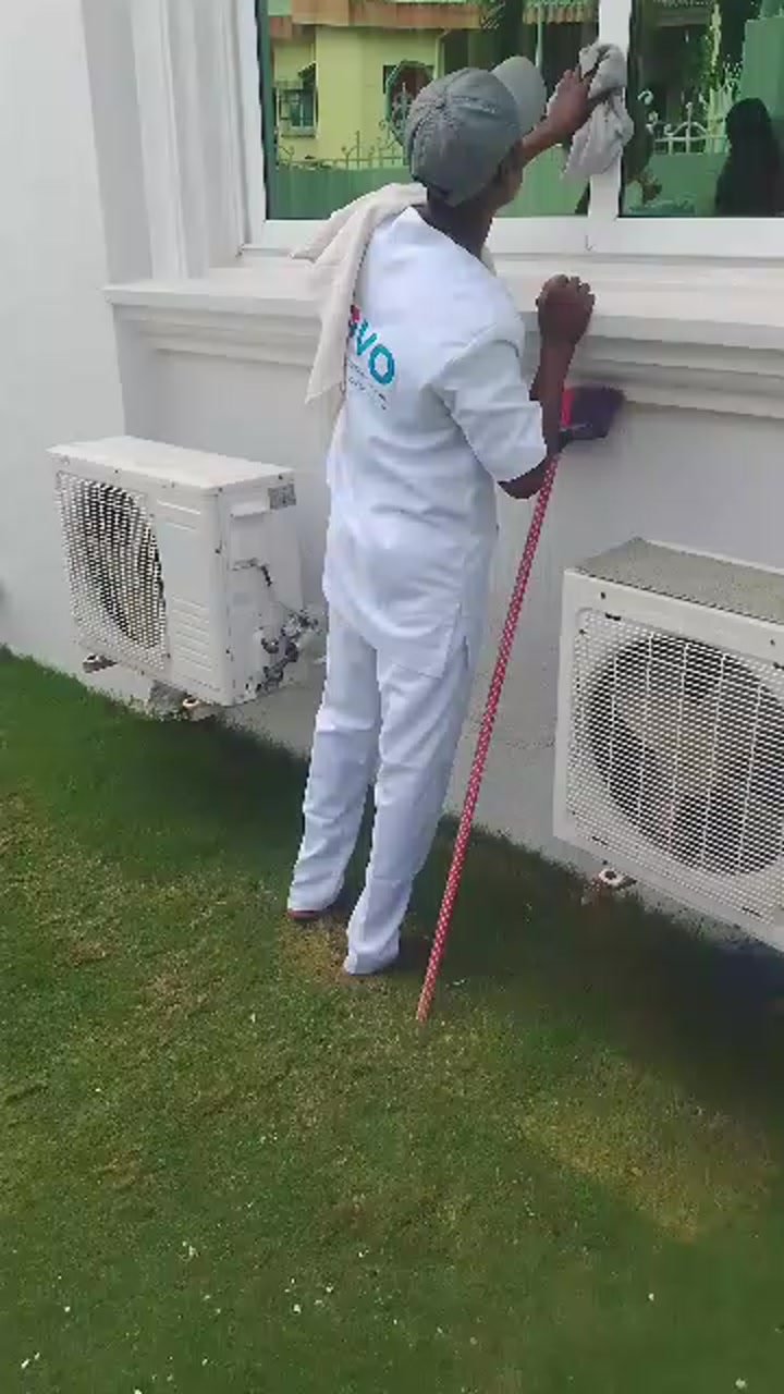 Agent Bovo en uniforme blanc nettoyant une vitre à Cotonou